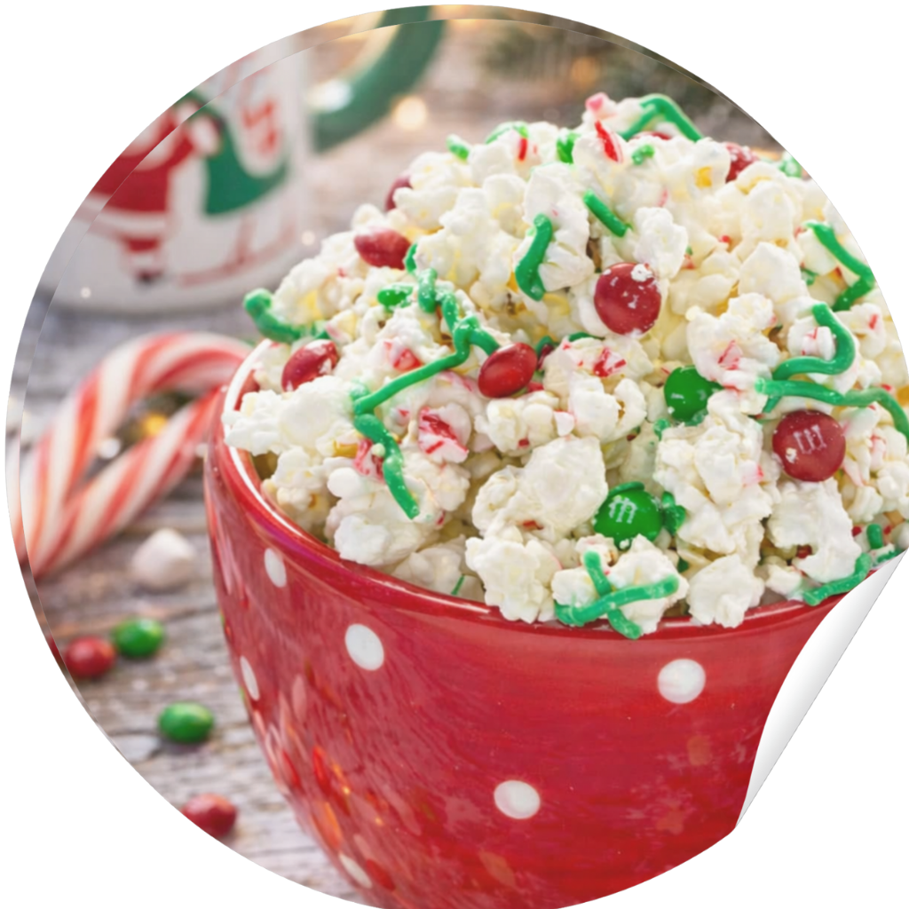 Festive Christmas popcorn coated in white chocolate with red and green M&M’s, styled with holiday decorations and fairy lights.
